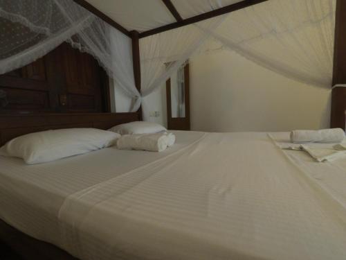 韦利格默Shine Breeze villa的一张白色大床,配有白色床单和枕头