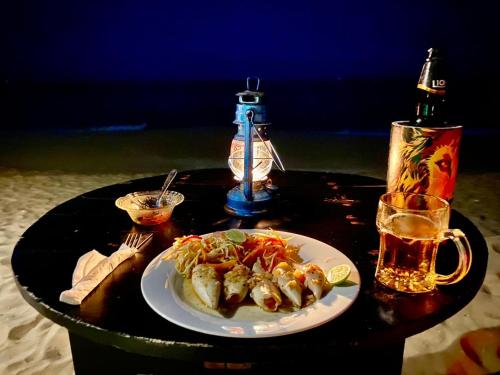 坦加拉Sasagara Beach Villa的一张桌子,上面放着一盘食物和一杯啤酒