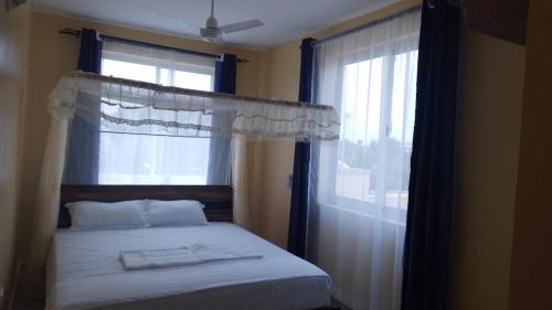 蒙巴萨Nyali cozy home的一间卧室配有床和带窗帘的窗户