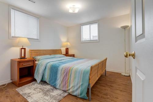 惠特比Comfortable Whitby 2 Bedroom Lower Suite的一间卧室配有床、床头柜和2扇窗户