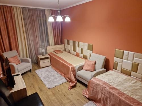 塞克萨德Centrum Business Apartman Szekszárd的一间卧室配有一张床、一张沙发和一把椅子