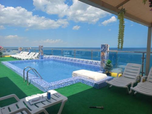 科威特Blue Waves Abu Halifa أمواج الخليج الزرقاء的一个带椅子和大海的阳台的游泳池