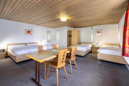 圣莫里茨弗兰科旅馆的一间设有两张床和一张桌子及椅子的房间