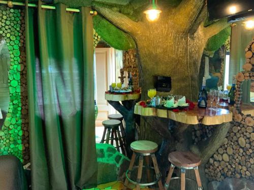 金特罗Hotel Boutique El Duende Mantagua的一间设有树主题酒吧的房间,配有凳子和桌子