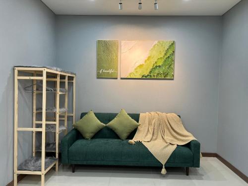胡志明市UPhoenix Home- HaDo Centrosa Garden的客厅里一张绿色的沙发,上面有绘画作品