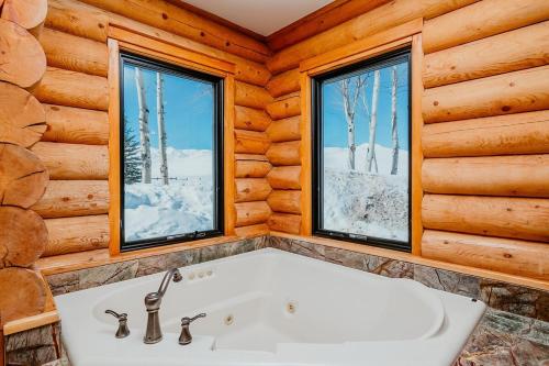 黑利Gorgeous Log Cabin Close to Town with Hot Tub的带浴缸的浴室和2扇窗户