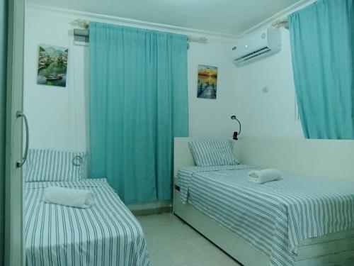 璜多里奥Acogedor apartamento a un paso de la playa的配有蓝色窗帘的客房内的两张床