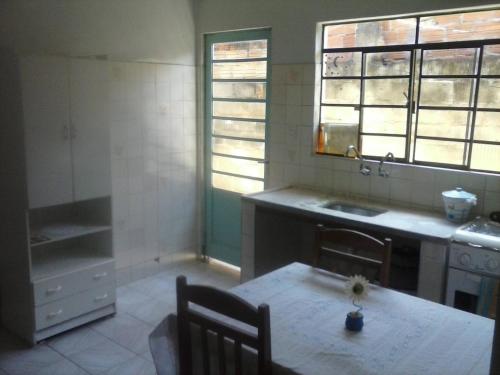 圣若泽杜斯坎普斯Hostel Sancris 2的厨房配有桌子、水槽和2扇窗户。
