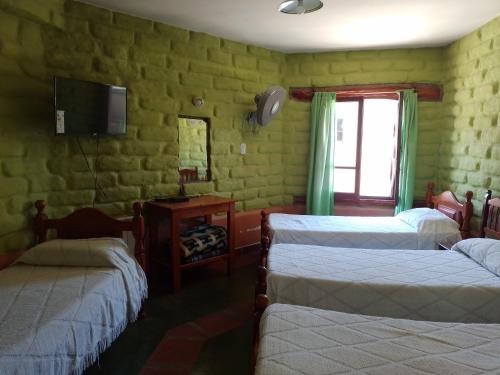 蒂尔卡拉Hotel El Jardin Dante的一间设有三张床的客房,墙上设有一台电视。