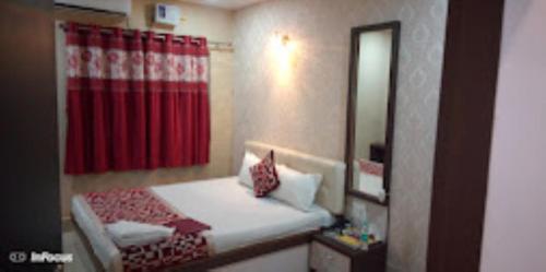锡尔杰尔Hotel Holiday inn , Kanakpur的一间小卧室,配有床和红色窗帘