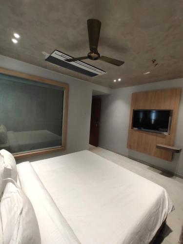 博帕尔Playotel Inn Aria, Bhopal的卧室配有一张白色大床和一台平面电视。