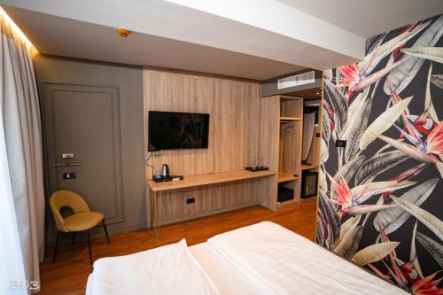 蒂米什瓦拉Cosmopolita Boutique Hotel的一间卧室配有一张床,墙上配有电视