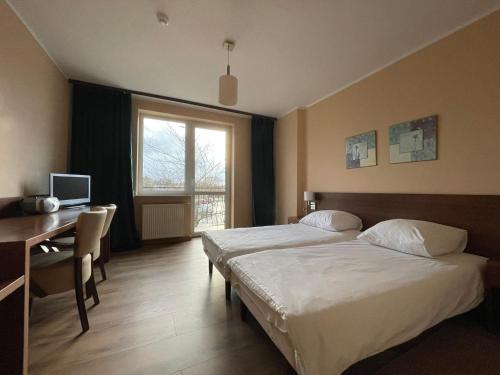 科沃布热格Motel Pieprzyk的酒店客房设有两张床、一张书桌和一个窗户。
