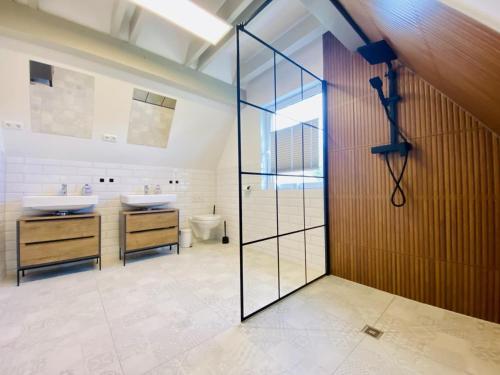 瓦尔内明德Sommerhaus am Bach的浴室设有2个水槽和玻璃淋浴间门。