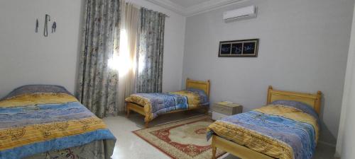 泰塔温Villa Mimosa Tataouine的一间卧室设有两张单人床和一个窗户。