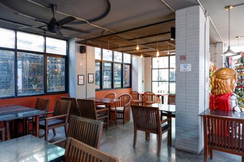 芭堤雅市中心18 Coins Budget Hotel的餐厅设有木桌、椅子和窗户。