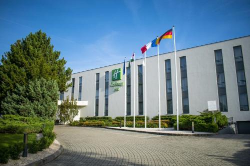 布达厄尔什Holiday Inn Budapest-Budaörs, an IHG Hotel的前面有两面旗帜的建筑