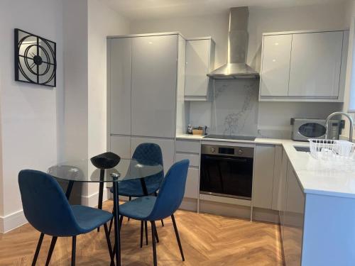 里克曼斯沃斯New 2 Bedroom Apartment Rickmansworth Town Centre的厨房配有玻璃桌和蓝色椅子