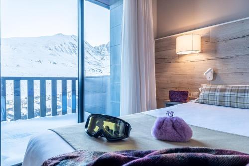 帕斯底拉卡萨Hotel Caribou的酒店客房设有一张床,享有雪覆盖的山脉美景