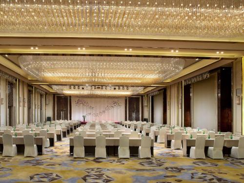 西安西安索菲特传奇酒店的一个带白色椅子和大吊灯的大型宴会厅