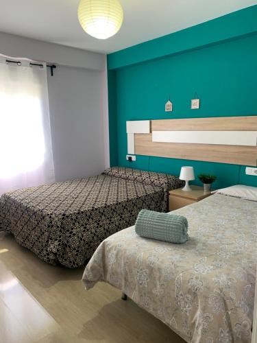 塞维利亚Bonito Apartamento en la Macarena的一间卧室设有两张床和蓝色的墙壁