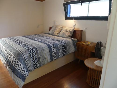 珀蒂蒂勒LE TUIT TUIT的一间卧室配有一张带蓝色棉被的床和窗户。