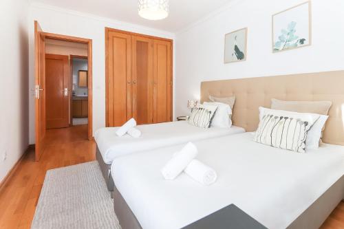 里斯本Laranjeiras Design by Homing的配有白色墙壁和木地板的客房内的两张床