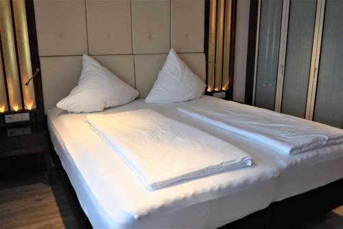 布尔Berggasthof Immenstein的一张带白色床单和枕头的床