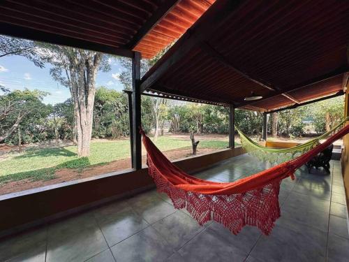 戈亚斯州上帕莱索Casa Amarela - Aconchegante e Familiar的带大窗户的客房内的吊床
