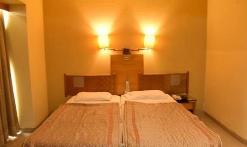 浦那FabHotel Prime Orchard Hospitality的一间卧室配有一张带两个白色枕头的床