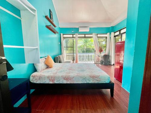 科罗尔Ngermid Oasis - Studio W/ Kitchenette & Pool View的一间拥有蓝色墙壁的卧室和一张位于客房内的床