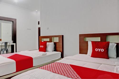 班达楠榜OYO 92945 Guest House Nusa Indah Syariah的客房内的两张床和红色枕头