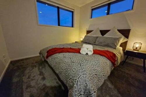 基督城Lovely Brand New Home 26的一间卧室配有一张大床和两条毛巾