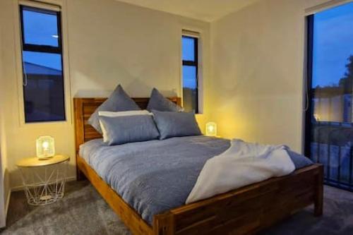 基督城Lovely Brand New Home 26的一间卧室配有一张带蓝色枕头的大床