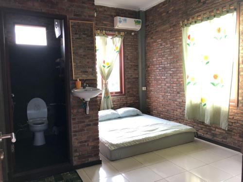 棉兰Bua Guest House的砖墙内带床和水槽的房间