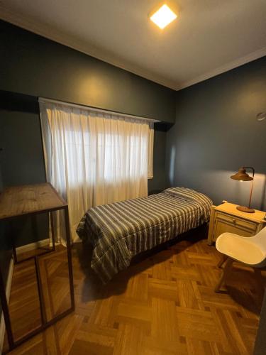 马德普拉塔Habitaciones Garay 3100的一间卧室配有一张床、一张桌子和一个窗户。