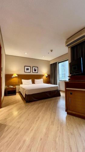 圣保罗Suíte Transamerica Executive Paulista的一间大卧室,配有一张床和一台电视