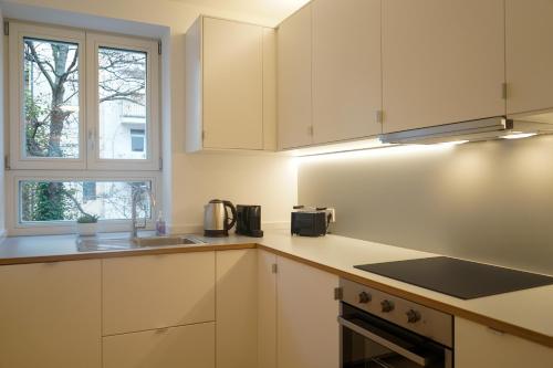 耶拿Appartement House Jena的厨房配有白色橱柜、水槽和窗户。