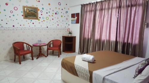 TuaranNew Orchid Hotel Tuaran的卧室配有一张床和一张桌子及椅子