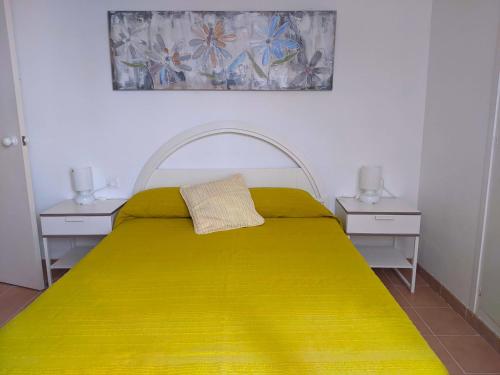 萨卡罗普拉亚公寓的一间卧室配有黄色的床和2个床头柜