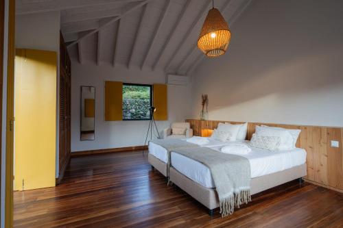 蓬塔德尔加达Carmo Country Villas的一间大卧室,配有两张床和一盏灯