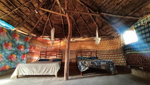 KachiouaneCampement Kaymba Lodge的带两张床和茅草屋顶的客房
