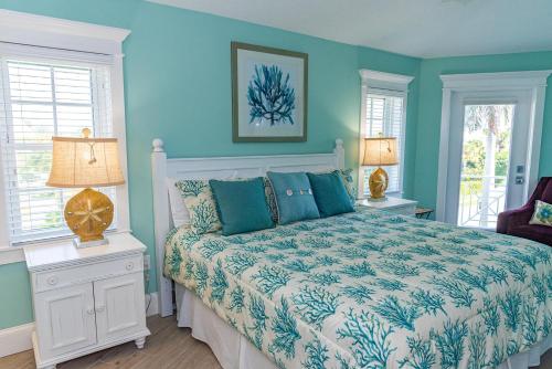 霍姆斯海滩Tiki Beach的一间卧室设有床铺、蓝色的墙壁和窗户。
