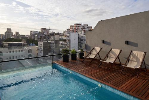 布宜诺斯艾利斯AQ Tailored Suites的阳台配有两把椅子,大楼内设有一个游泳池