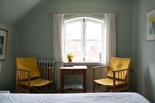 里伯Cafe Sallys bed and breakfast的一间卧室配有三把椅子、一张桌子和一个窗户。