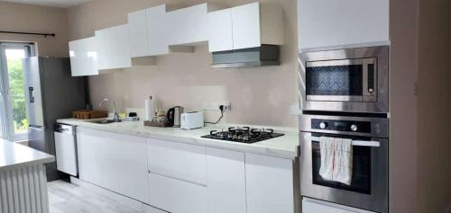 La FargueTIE-2 bedroom luxury home的白色的厨房配有炉灶和微波炉。