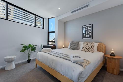卧龙岗KULA Wollongong的一间卧室设有一张大床和两个窗户。