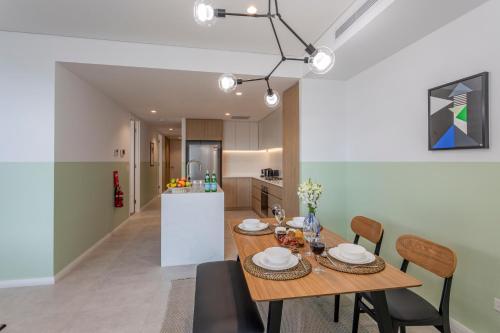 卧龙岗KULA Wollongong的厨房以及带木桌和椅子的用餐室。