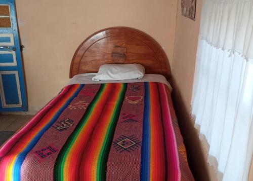 奥科苏尤BLUE SKY Amantani Lodge的床上有五颜六色的毯子