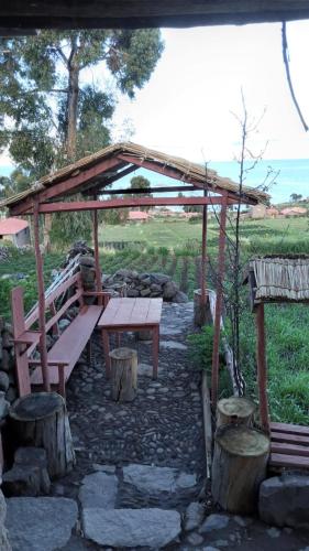 奥科苏尤BLUE SKY Amantani Lodge的木亭下的野餐桌和长凳